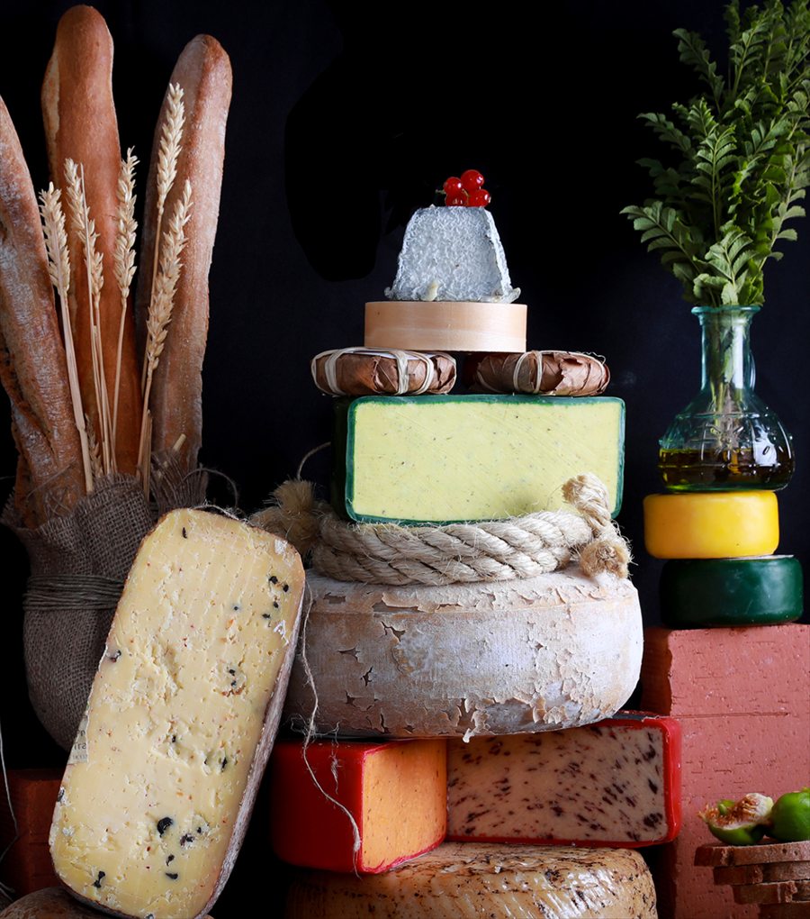 A tower of aged wheels and a goat's-milk pyramid beside baguettes